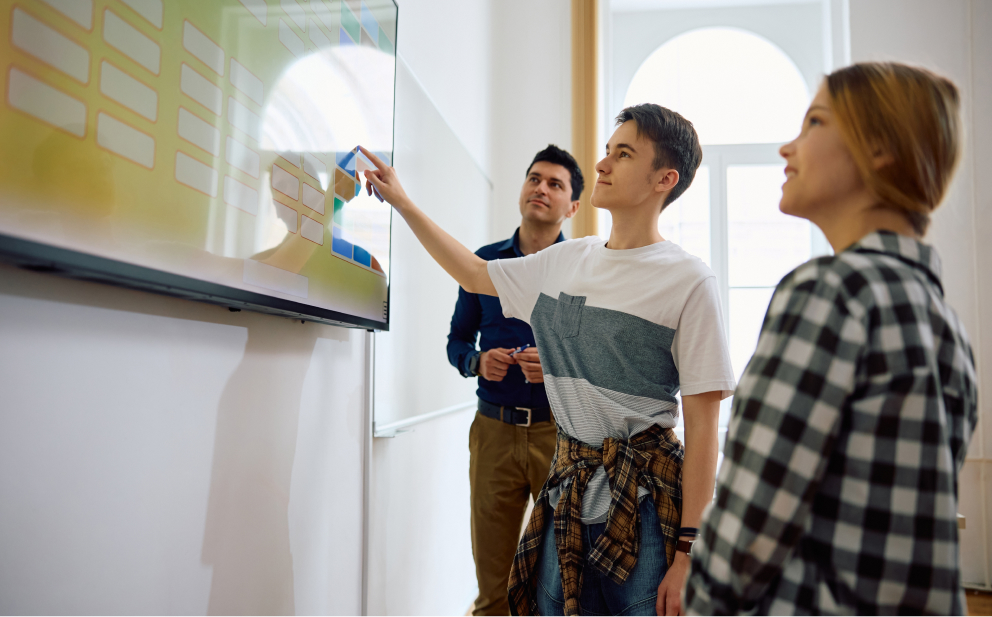 Student touching screen of mounted interactive panel while others look on