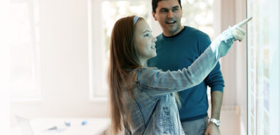 Middle school age girl touches interactive screen with teacher looking on