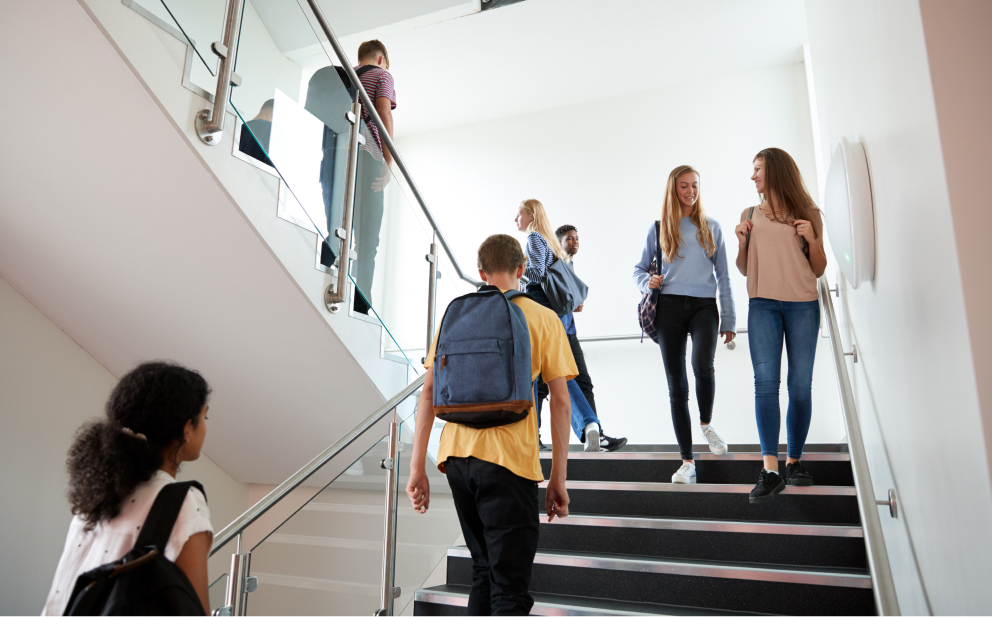 High school age students walking in stairwell in campus building